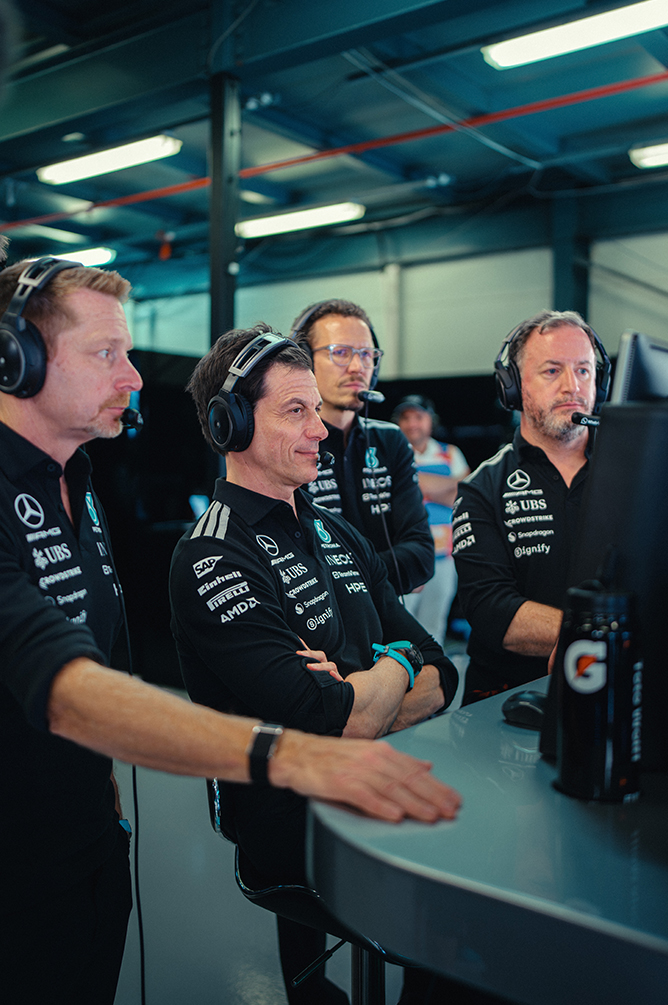 Membres de l’équipe de Formule 1 regardant la course dans la voie des stands.