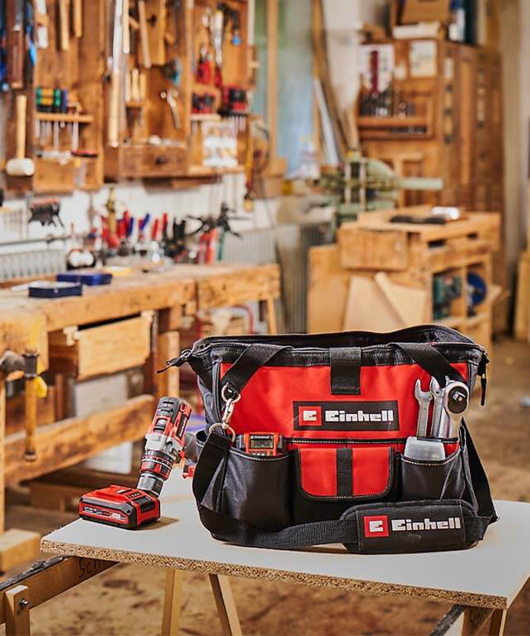 Tool bag and cordless screwdriver lay on a table in a workshop